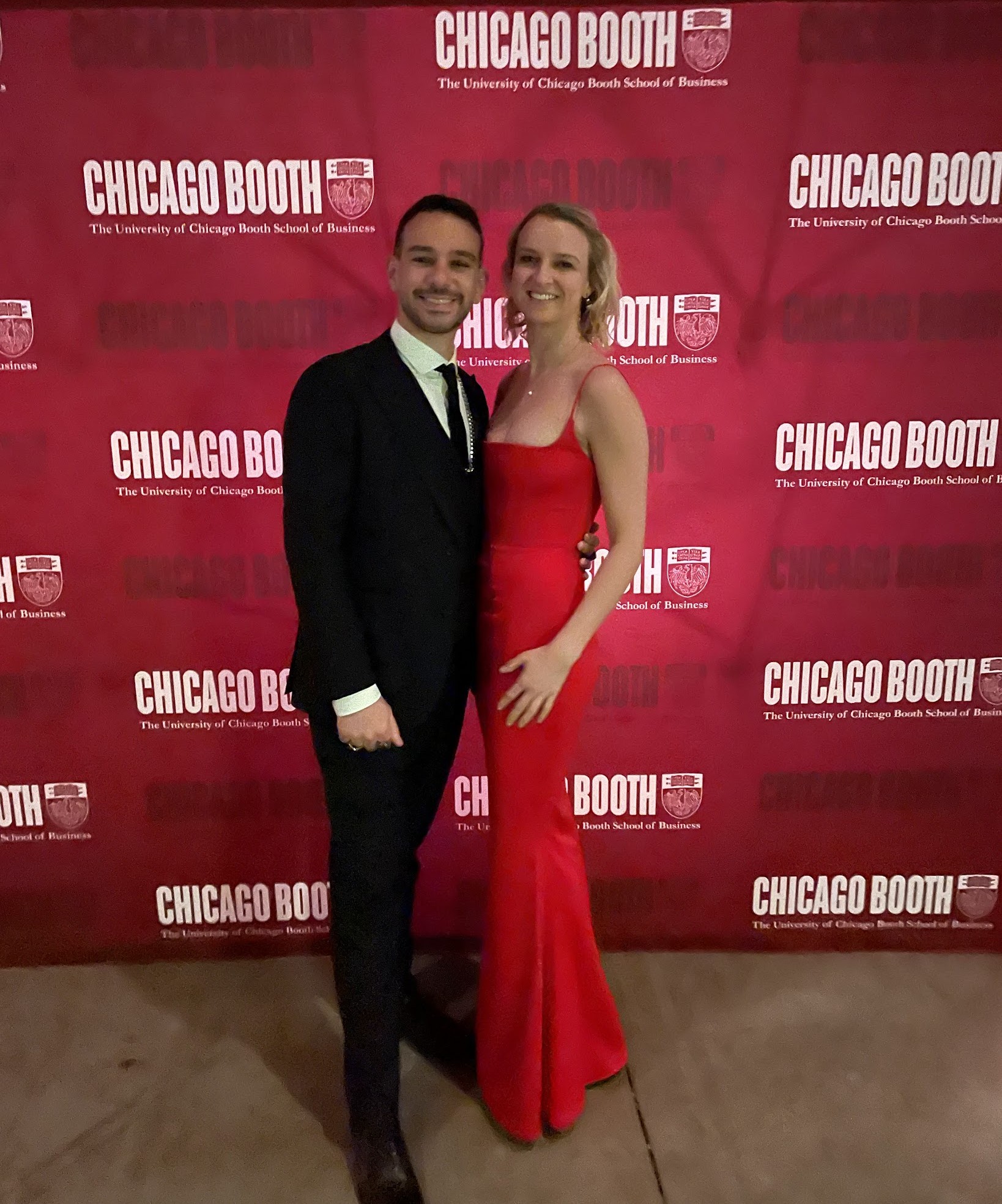 Mark Khoury and his wife at a Chicago Booth gala in front of a Chicago Booth backdrop